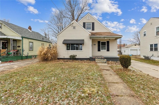 bungalow featuring covered porch, concrete driveway, central AC unit, and an outbuilding