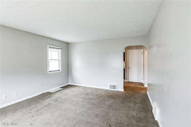 carpeted empty room featuring arched walkways, visible vents, a textured ceiling, and baseboards