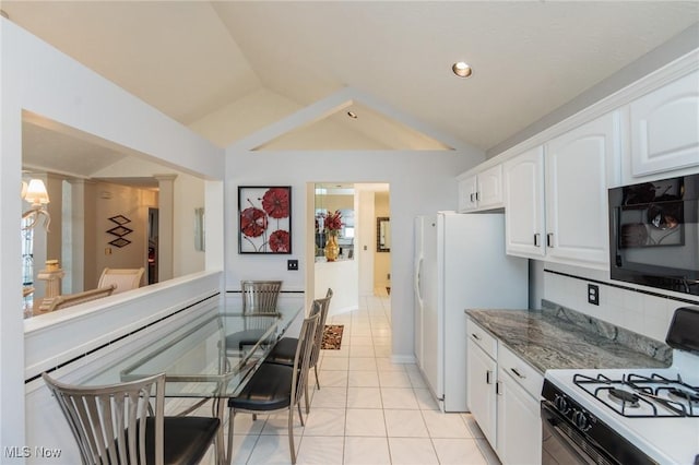 kitchen with white cabinets, lofted ceiling, freestanding refrigerator, backsplash, and gas stove