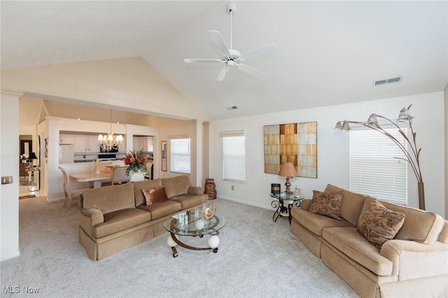 living room with ceiling fan with notable chandelier, high vaulted ceiling, visible vents, and light colored carpet