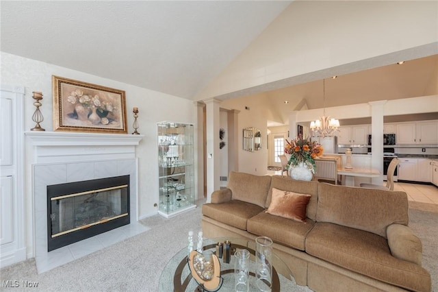 living room featuring light carpet, a tile fireplace, high vaulted ceiling, ornate columns, and a chandelier