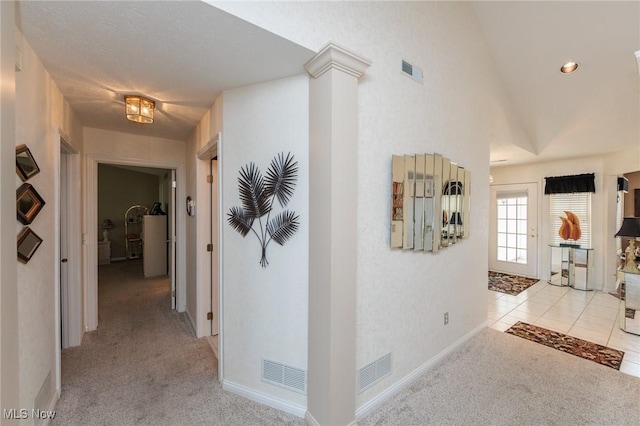 hall with light tile patterned floors, lofted ceiling, visible vents, light carpet, and ornate columns