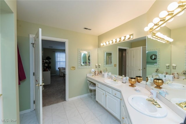 bathroom featuring double vanity, a sink, visible vents, and baseboards