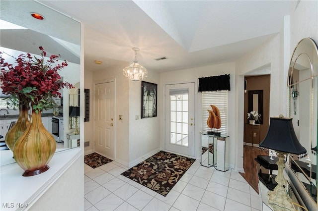 foyer featuring visible vents, a notable chandelier, baseboards, and light tile patterned flooring