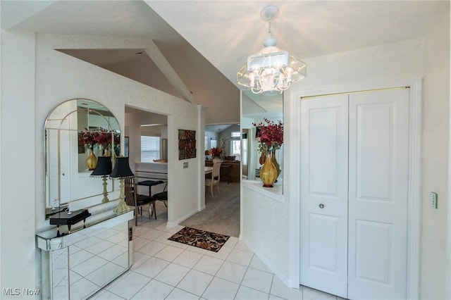 foyer with light tile patterned floors, vaulted ceiling, and an inviting chandelier