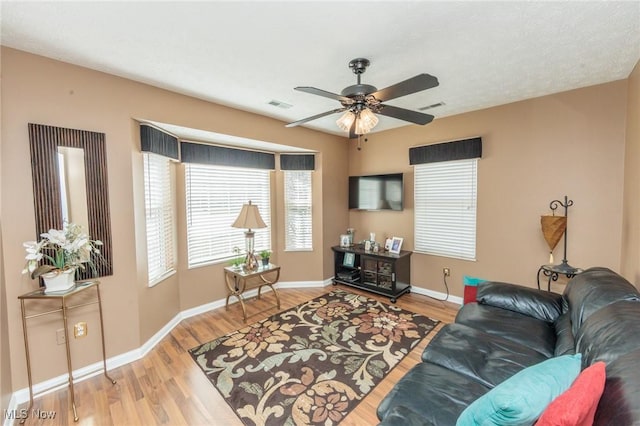 living room featuring visible vents, ceiling fan, baseboards, and wood finished floors