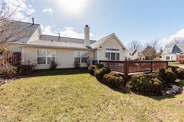 back of house featuring a chimney, a lawn, and a wooden deck