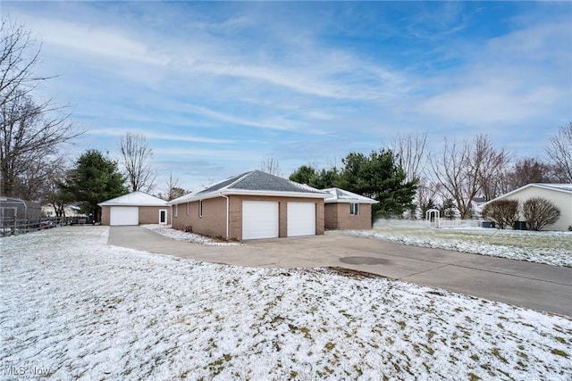 view of snow covered exterior featuring a detached garage and an outdoor structure