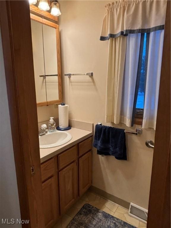 bathroom with tile patterned flooring, visible vents, baseboards, and vanity