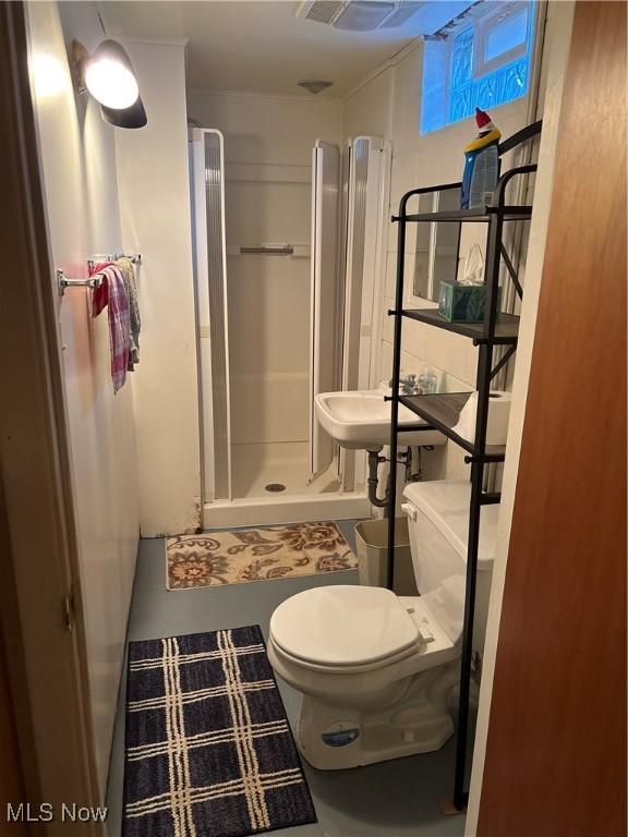 bathroom featuring toilet, a shower stall, and a sink