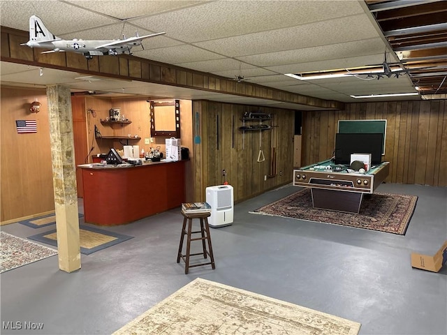 finished below grade area featuring pool table, a drop ceiling, and wooden walls