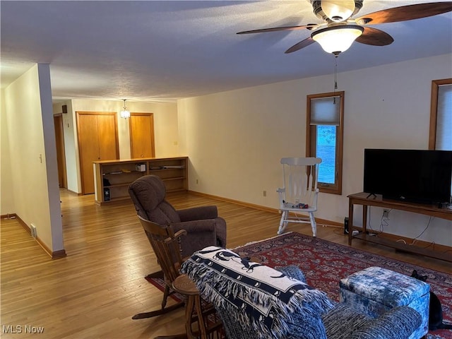 living room with light wood-type flooring, baseboards, and a ceiling fan