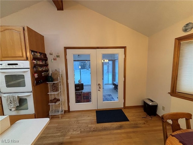 entryway featuring lofted ceiling, light wood-style flooring, baseboards, and french doors