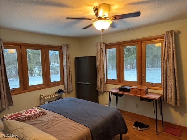 bedroom featuring a textured ceiling, a ceiling fan, and wood finished floors