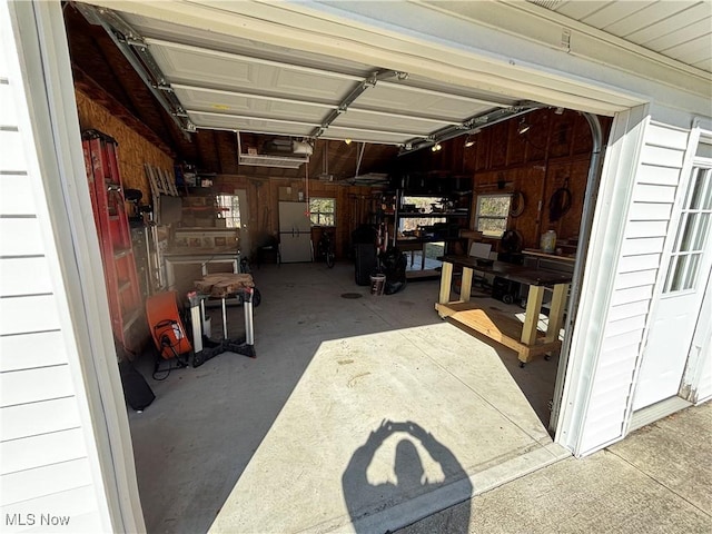 garage with wood walls and freestanding refrigerator