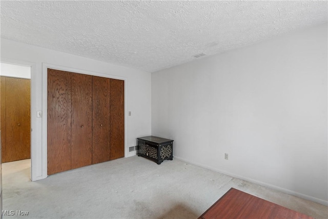 carpeted bedroom featuring a textured ceiling, visible vents, and a closet