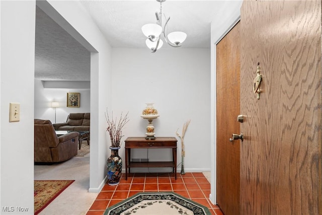 hall featuring tile patterned flooring, a textured ceiling, baseboards, and a notable chandelier