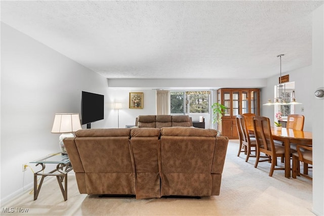 living room with a textured ceiling, light carpet, and baseboards