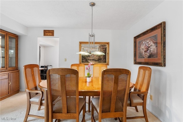 dining area featuring a textured ceiling and light colored carpet