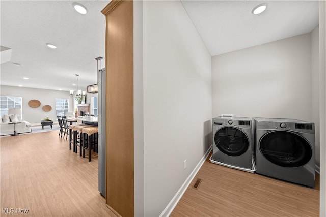 laundry area featuring laundry area, light wood-style flooring, separate washer and dryer, and recessed lighting