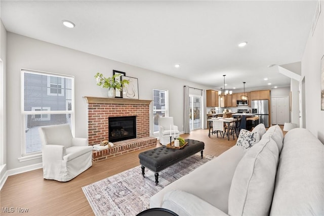 living area with recessed lighting, a fireplace, light wood-style flooring, and baseboards