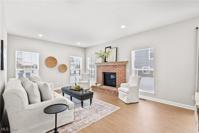 living room featuring visible vents, a fireplace, baseboards, and wood finished floors