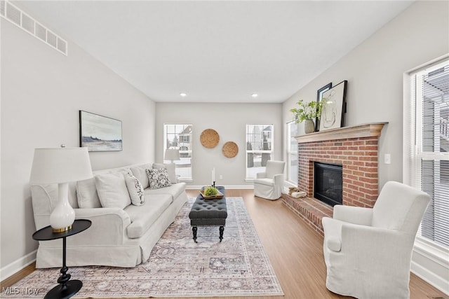 living area featuring recessed lighting, a fireplace, wood finished floors, visible vents, and baseboards