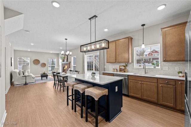 kitchen featuring a kitchen island, a sink, light countertops, dishwasher, and tasteful backsplash