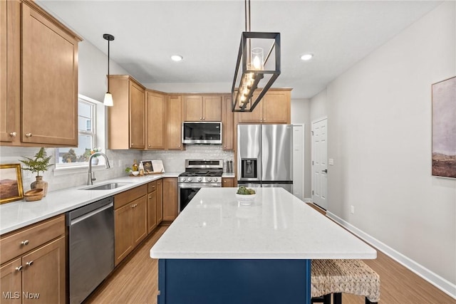 kitchen with stainless steel appliances, light wood-style flooring, decorative backsplash, a sink, and a kitchen island