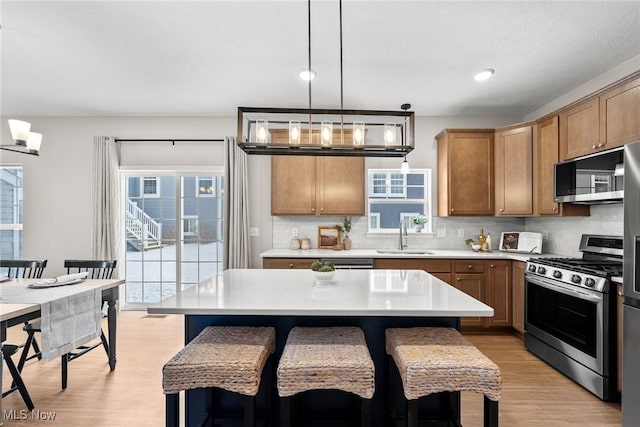 kitchen with stainless steel gas stove, a breakfast bar area, light countertops, and a sink