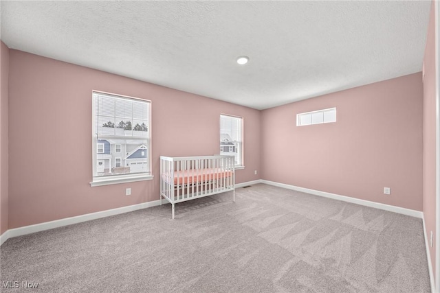 unfurnished bedroom with a textured ceiling, carpet flooring, and baseboards