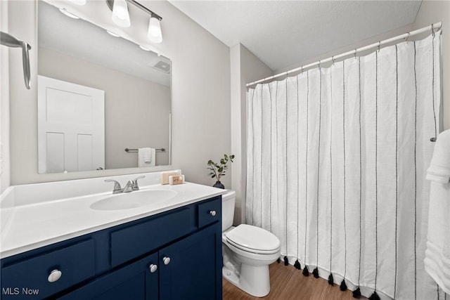 full bath with toilet, wood finished floors, and vanity