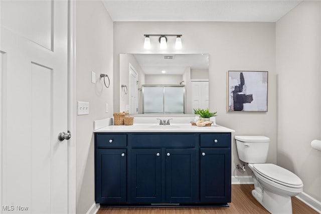 full bath featuring a stall shower, baseboards, toilet, wood finished floors, and vanity