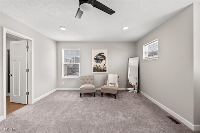 sitting room featuring a textured ceiling, carpet flooring, a ceiling fan, and baseboards