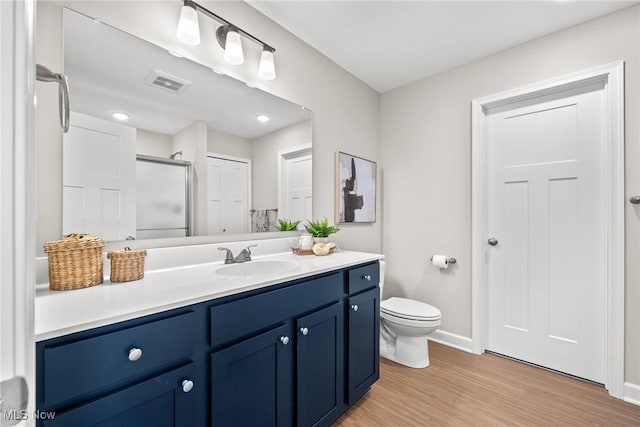 full bath featuring visible vents, toilet, a stall shower, vanity, and wood finished floors