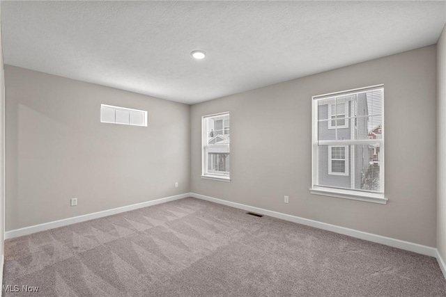 unfurnished room featuring carpet floors, visible vents, a textured ceiling, and baseboards