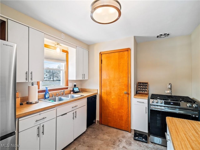 kitchen with appliances with stainless steel finishes, white cabinets, a sink, and wooden counters