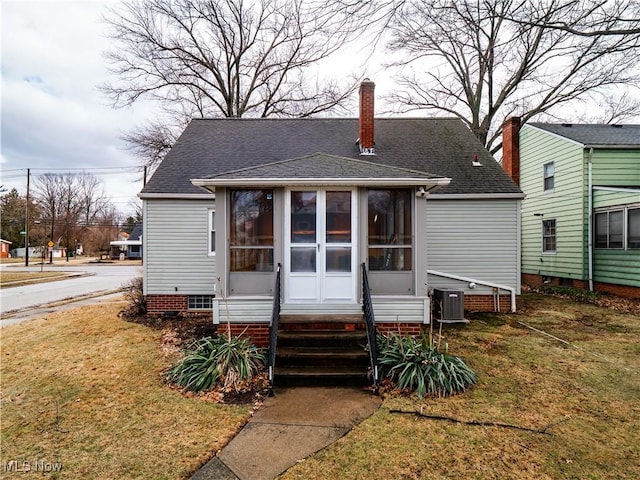 view of front facade featuring crawl space, a sunroom, a shingled roof, and a front yard