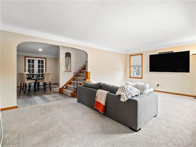 living room featuring arched walkways, carpet floors, stairway, and baseboards