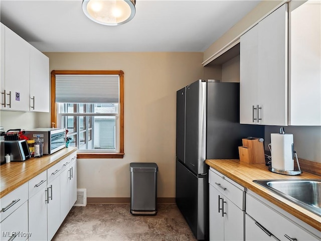 kitchen featuring visible vents, wood counters, stainless steel appliances, white cabinetry, and a sink