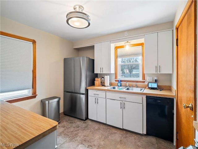 kitchen with freestanding refrigerator, white cabinets, dishwasher, and a sink