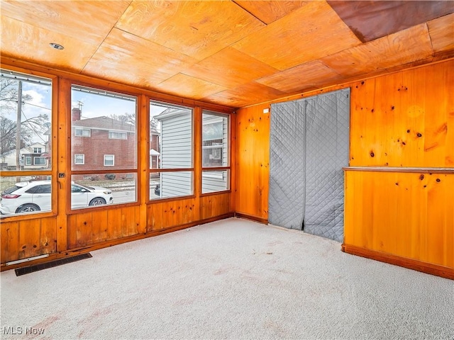 empty room with wood ceiling, carpet flooring, and wood walls