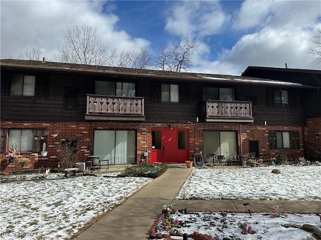 view of front of home featuring brick siding and a balcony