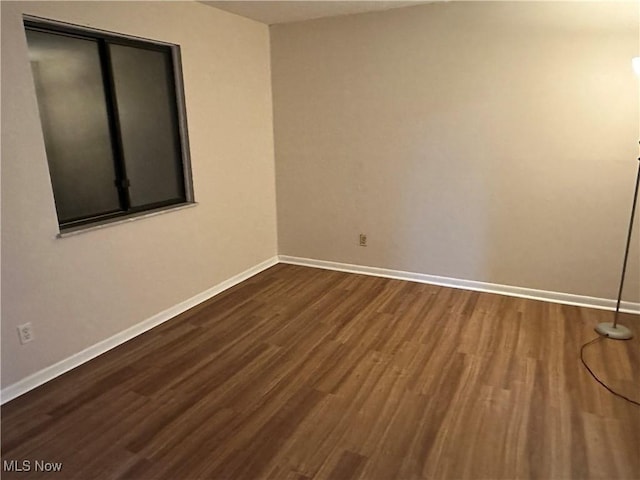 empty room featuring dark wood-style floors and baseboards