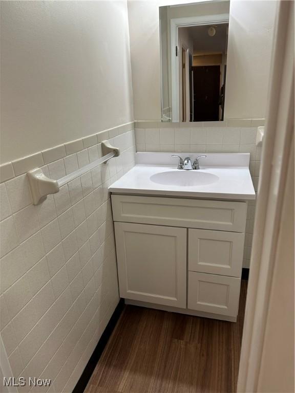 bathroom featuring a wainscoted wall, tile walls, wood finished floors, and vanity