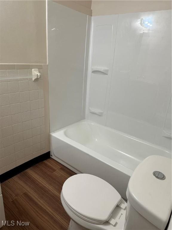 full bathroom with wainscoting, toilet, wood finished floors, tile walls, and shower / bathing tub combination