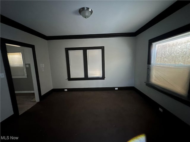 empty room featuring baseboards and crown molding