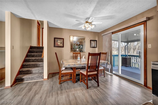 dining space featuring ceiling fan, a textured ceiling, wood finished floors, and baseboards