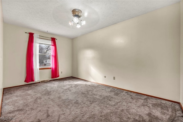 carpeted empty room with a ceiling fan, visible vents, a textured ceiling, and baseboards