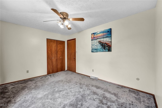 unfurnished bedroom with baseboards, visible vents, a ceiling fan, a textured ceiling, and carpet flooring